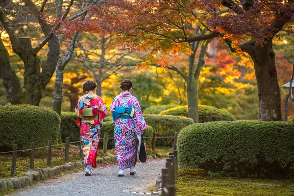 Geleneksel Japon elbiseli genç kadınlar Kenrokuen Bahçesinde yürüyor
