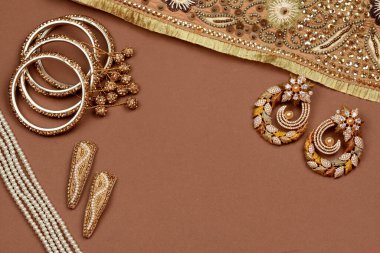 Kahverengi arka planda inci mücevher, altın eşarp, inci bilezik, inci saç tokası, inci kolye, inci küpeler. Tarz, moda ve mücevher tasarımı. Hint geleneksel mücevherleri.