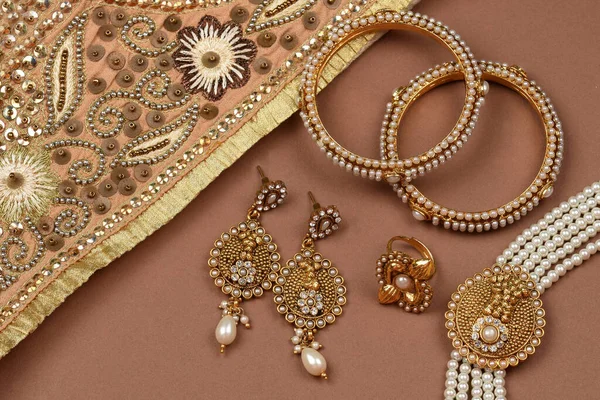 Pearl Jewelry on a brown background, Golden scarf, Pearl bracelet jewelry background, pearl necklace, pearl earrings, finger ring.Style, fashion and design of jewelry. indian traditional jewellery