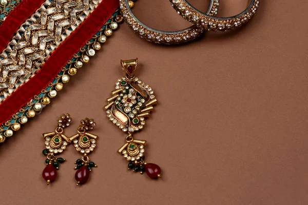 Antique jewellery on a brown background, Golden scarf, Gold bracelet,jewelry background, Gold necklace, Gold earrings, finger ring.Style, fashion and design of jewelry. indian traditional jewellery