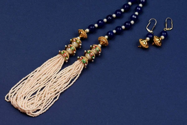 Indian traditional jewelry on blue background with earrings.pearl and blue stone necklace,Luxury female jewelry, Indian traditional jewellery,Bridal Gold wedding jewellery