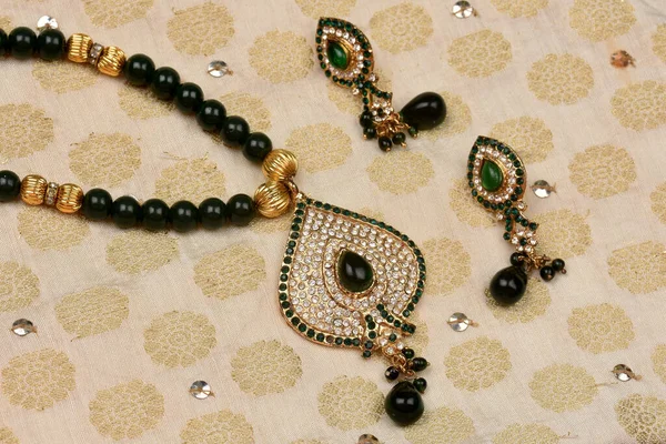イヤリングと布の上に置かれたインドの伝統的なジュエリー ダイヤモンドと緑の石のペンダント 高級女性のジュエリー インドの伝統的なジュエリー ダイヤモンドのイヤリング ブライダルゴールドのウェディングジュエリー — ストック写真