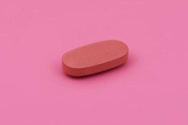 Oval şekilli ilaç tableti pembe arka planda, düz yerde. Uzayı kopyala Tıp kavramları. Minimalist soyut kavram. bebek pembe renk arkaplanı