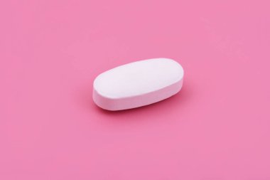 Pembe arka planda beyaz ilaç tableti, Top view. Düz yatıyordu. Uzayı kopyala Tıp kavramları. Minimalist soyut kavram. bebek pembe renk arkaplanı