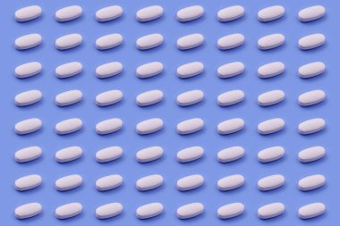 Mavi arka planda beyaz ilaç tableti, tıp yaratıcı kavramları. Renkli kağıdın arka planına sahip minimal biçim. Moda renkler, moda desen