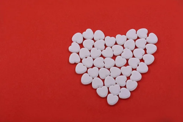 心臓の丸薬からの心臓の形 赤い背景にハート型の丸薬 人々を助ける薬 — ストック写真