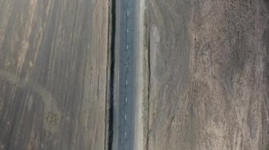 Hava aracı görüntüsü, çöldeki ıssız bir yolda giden bir minibüsün dikey üst görüntüsü. Konum Moğolistan güneşli öğleden sonra