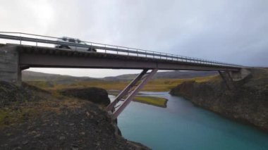 Araba İzlanda 'da pembe bir köprüden geçiyor. Bulutlu bir gün