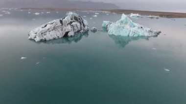 İzlanda Jokursarlon gölündeki buzdağlarının insansız hava aracı görüntüsü. Bulutlu öğleden sonra, alçak irtifa uçuşu