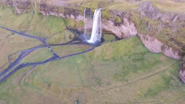 Güney İzlanda 'daki Seljalandsfoss şelalesinin insansız hava aracı görüntüsü arkasında yürüyebileceğiniz güzel bir şelale. Yüksek irtifa uçuşu