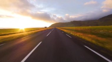 İzlanda 'da hızlı sürüş. Gün batımında yol görünümü.