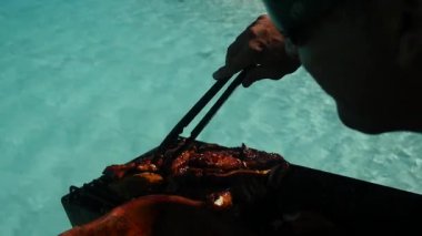 Teknesinde barbekü yapan bir adamın eli. Temiz su Fransız Polinezyası