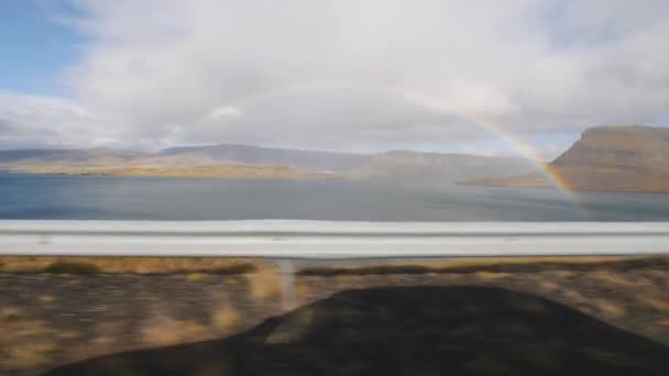 Arco iris a lo largo de una carretera costera en Islandia. Vista desde un coche — Vídeos de Stock