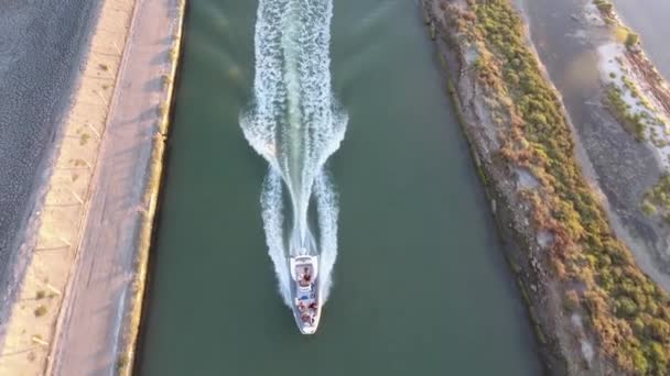 Vertikale Ansicht einer Drohne, die einem schnellen Boot in einem Kanal bei Sonnenuntergang folgt. — Stockvideo