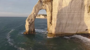 Etretat 'ın doğal bir kaya kemeri üzerinde uçmak. Normandiya Fransa, insansız hava aracı manzaralı gün batımı