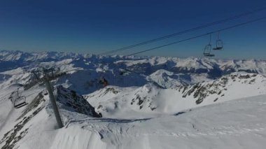 La Plagne Fransa 'da bir teleferik boyunca kayakçılarla uçan insansız hava aracı..