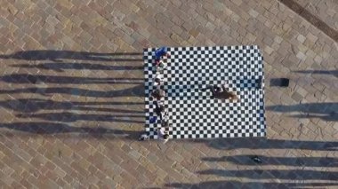 Çocuklar dama tahtası desenli bir halıda dans ediyorlar.