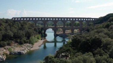 Pont du Gard, ağaçların, Gardon nehrinin ve Fransa 'nın eski su kemerinin üzerindeki kemerden geçen bir hava aracı.