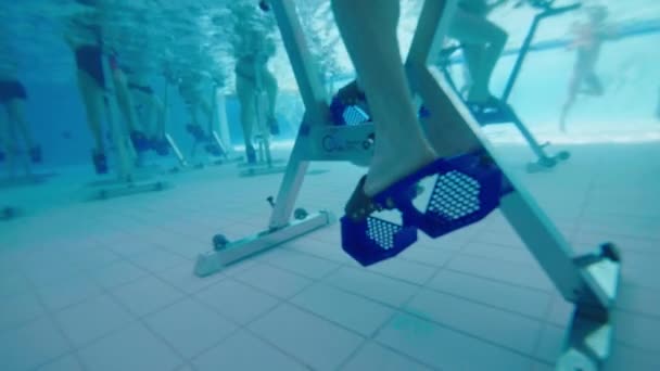 Cerrar la toma submarina de un hombre pedaleando en una moto acuática en una piscina — Vídeo de stock