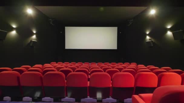 Viajando sobre a fila do assento do cinema vermelho com tela no fundo. Teatro de cinema — Vídeo de Stock