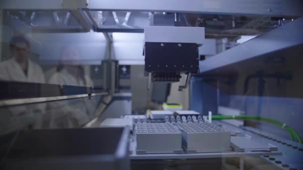 Automatiserat pipetteringssystem i drift i ett laboratorium med forskare på baksidan — Stockvideo