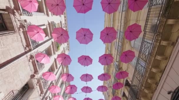 Spacerując pod różowymi parasolami widok z dołu. Różowy październik słoneczny dzień niebieski — Wideo stockowe