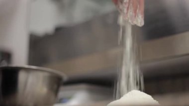 Şef bir kâseden bir avuç un alır ve onu mutfak masasına döker. Restoranda pizza yapmak için dağ gibi un.