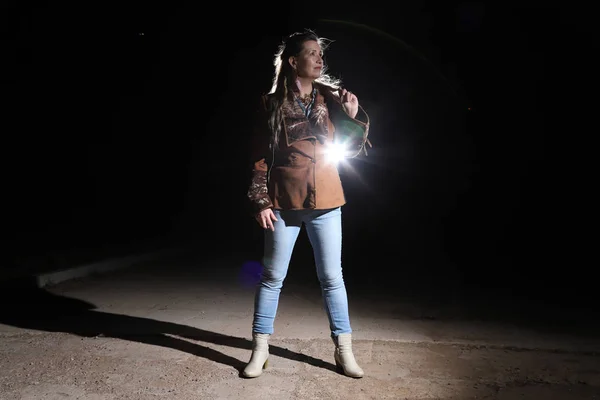 Ugly woman on night street, light behind her and black background