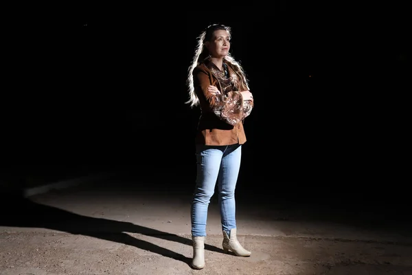 Ugly woman on night street, light behind her and black background