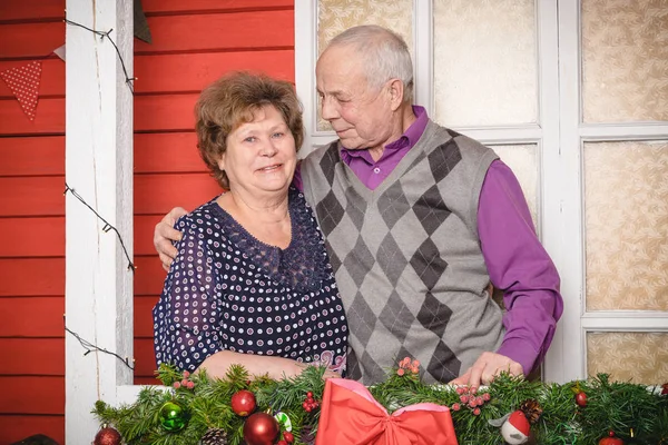 Happy senior couple at home in the room decorated for Christmas and New year