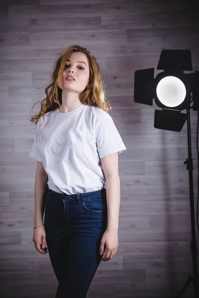 Girl in white tee-shirt in studio near black spotlights