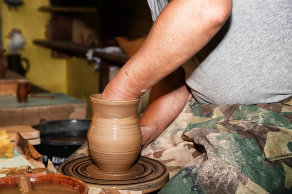 Hands of Potter man sculpt something by clay in a cozy craft workshop