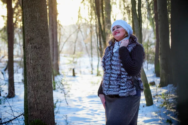 Plump woman in a nice winter forest full of snow. Lady in fur coat