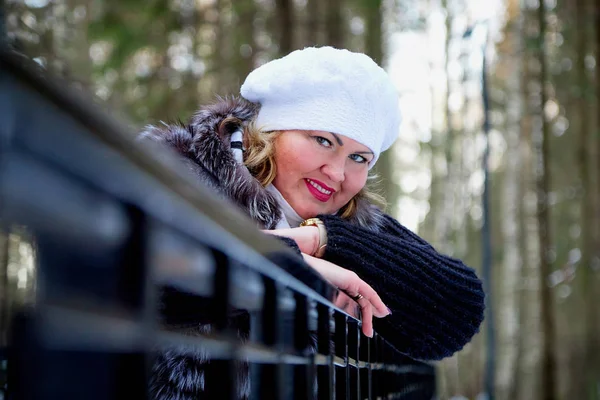 Portrait of beautiful plump woman in a nice winter forest full of snow. Lady in fur coat