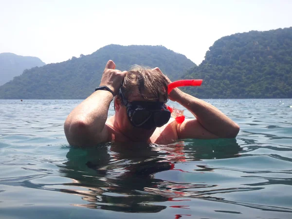 A man with a mask and snorkel is going to dive into the sea. Nature landscape