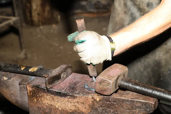 Blacksmith working on an anvil. Hands of master showing tourists the work of a blacksmith in Dudutki in Belarus