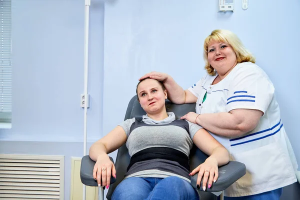 Experienced doctor fat woman taking care of a sick girl on the couch in the medical office