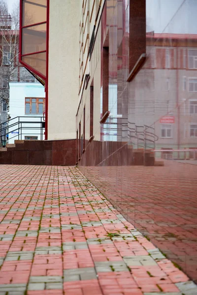 Red marble wall of the house with the reflection of the landscape in it