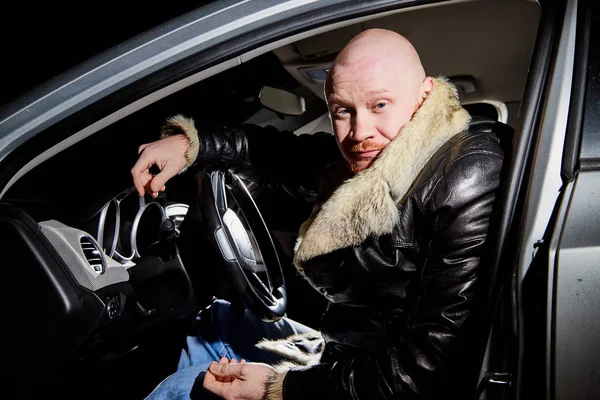 Male driver in a leather jacket in the car in the dark time. Night unusual photo shoot. Night photo shoot