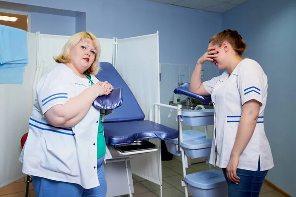 Experienced doctor fat woman teaching aspiring young doctor how to do peculiarities of medical work