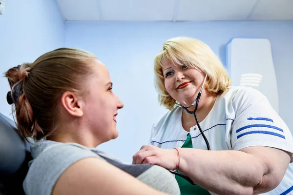 Experienced doctor fat woman taking care of a sick girl on the couch in the medical office