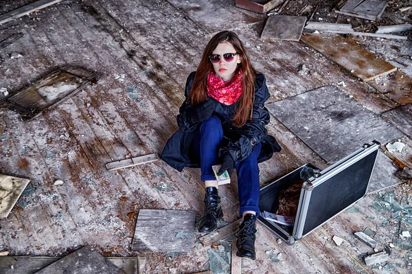 Girl in a black cloak with a diplomat and money in a ruined room. A spy in a secret meeting. Unusual photo shoot