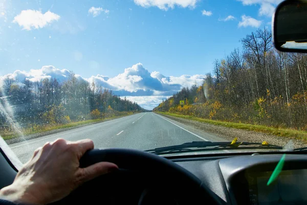 Track from the car window and white clouds on blue sky. Natural landscape