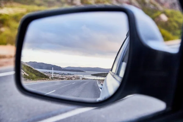 Car Mirror and reflection of the road and sky in it