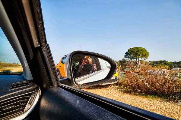 Car Mirror and reflection of traveller photographer and sky in it