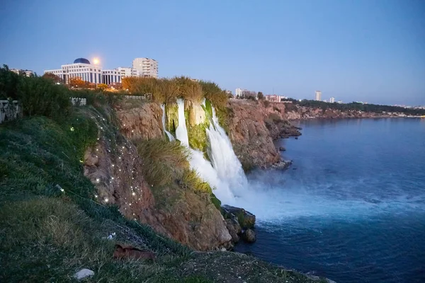 Waterfall with water falling in sea in the evening time with sunset. Waterfall Duden at Antalya in Turkey. Concept of nature travel
