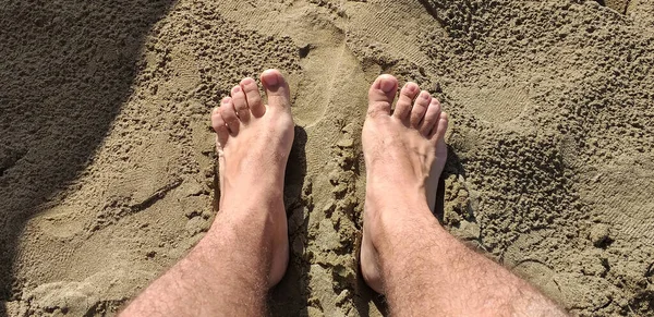 Human feet rest on the warm sand of Versilia Tuscany.