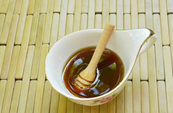 Дерев'яна медова ложка в чашці на бамбуковій тарілці — стокове фото
