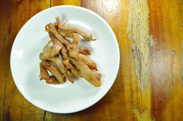 Gebratene Scheiben Schweinefleisch stechen mit Holzstab auf Teller — Stockfoto