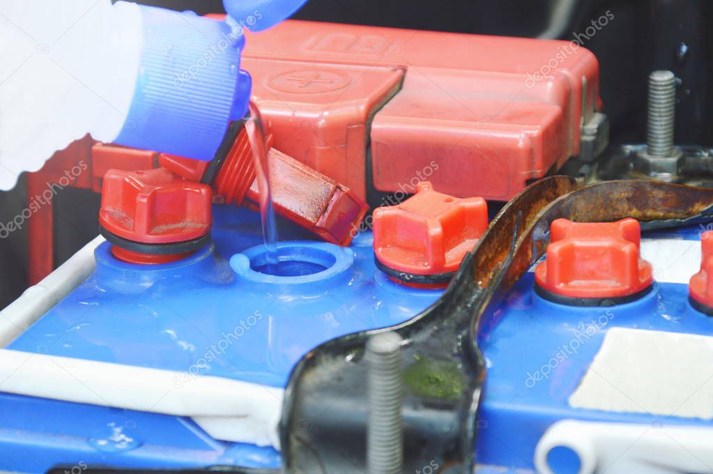 distilled water flowing from plastic bottle filling in car batteries
